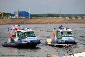 dwie motorówki policji wodnej na wodach zalewu, w tle widoczna betonowa tama z wiaduktem