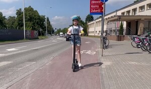 Dziewczynka na hulajnodze jedzie ścieżką rowerową
