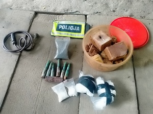 przedmioty zabezpieczone przez policję naboje, brunatna substancja w plastykowym pojemniku i zawiniątka białego proszku