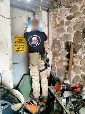 policjant podpodziału kontrterrorystycznego bada możliwość wejścia do pomieszczenia za drzwiami