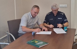 KOMENDANT POWIATOWY POLICJI I WÓJT GHMINY TOMASZÓW MAZOWIECKI SIEDZĄC PRZY STOLE PODPISUJĄ DOKUMENT POROZUMIENIA