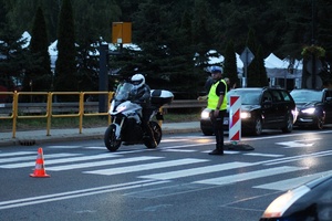 policjanci ruchu drogowego regulujący przejazd pojazdów zapewniają bezpieczeństwo pieszym