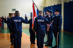 nowo przyjęci policjanci składają ślubowanie przed sztandarem policji.