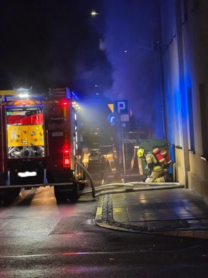 pojazd straży pożarnej z lewej strony, z prawej strony Strażak wykonuje czynności na miejscu zdarzenia