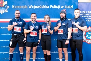 Pięcioosobowa drużyna tomaszowskich policjantów w strojach sportowych na Niebieskim Biegu Niepodległości 2024 w lesie łagiewnickim na terenie Łodzi.