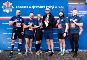 Pięcioosobowa drużyna tomaszowskich policjantów w strojach sportowych na Niebieskim Biegu Niepodległości 2024 w lesie łagiewnickim na terenie Łodzi.