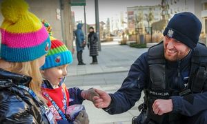 Policjant kuca przy dwójce dzieci.