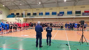 Rozpoczęcie turnieju siatkowego na terenie hali sportowej drużyny stoją w grupach podczas okolicznościowych przemówień.