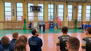 Rozpoczęcie turnieju siatkowego na terenie hali sportowej drużyny stoją w grupach podczas okolicznościowych przemówień.