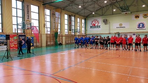 Rozpoczęcie turnieju siatkowego na terenie hali sportowej drużyny stoją w grupach podczas okolicznościowych przemówień.