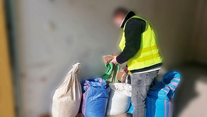 Policjant zabezpiecza worki z nielegalną krajanką tytoniową.