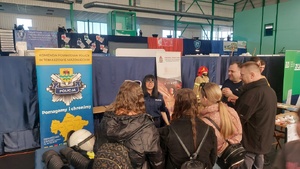 Policjanci na stoisku informacyjnym podczas VII Targów Pracy i Edukacji w Tomaszowie Mazowieckim wraz z uczestnikami.