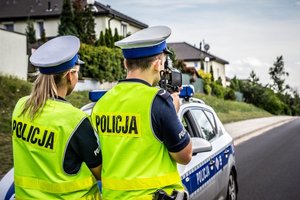 Policjanci z ruchu drogowego stoją przy radiowozie.