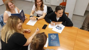 Kandydaci do służby siedzą przy stołach wypełniając formularze rekrutacyjne.