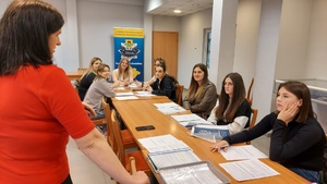 Kandydaci do służby siedzą przy stołach wypełniając formularze rekrutacyjne.