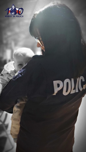 Policjantka w mundurze trzyma na rękach małe dziecko.