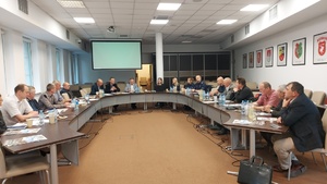 Uczestnicy spotkania w tym umundurowana policjantka i policjant siedzą przy stołach ustawionych w owal.