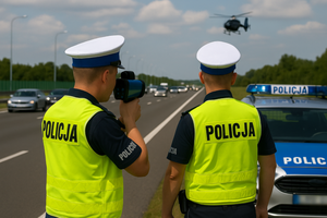 Dwóch policjantów , jeden mierzy prędkość, na niebie helikopter na drodze stoi radiowóz.