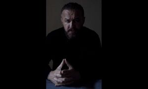 Mężczyzna siedzi przy stole ze złożonymi rękoma.