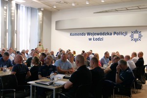 Aula, za mównicą funkcjonariusz Straży Granicznej, policjanci siedzą na krzesłach.