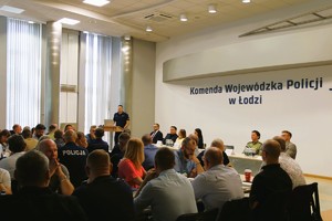 Aula, za mównicą funkcjonariusz Straży Granicznej, policjanci siedzą na krzesłach.
