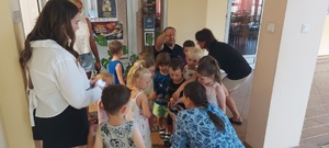Dzieci wraz z opiekunkami i policjantem, zwiedzają komendę, i oglądają radiowóz.