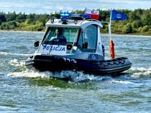 Funkcjonariusz Policji za sterami nowej łodzi policyjnej  płynącej po Zalewie Sulejowskim.