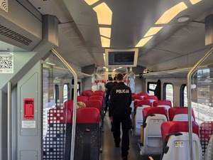 Umundurowany Policjant stojący na korytarzu pociągu.