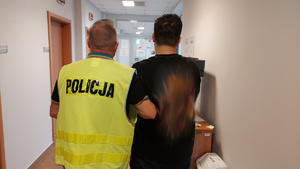Funkcjonariusz Policji z zatrzymanym, poszukiwanym trzydziestolatkiem.