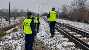 Umundurowani funkcjonariusze Policji oraz Służby Ochrony Kolej patrolujący obszar przy torach.