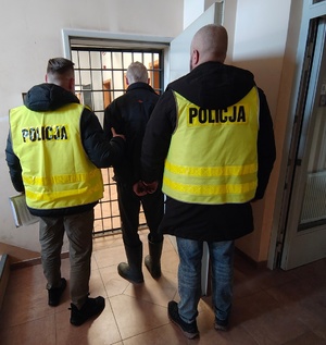 Umundurowani funkcjonariusze Policji z zatrzymanym sprawcą kradzieży pojazdu.