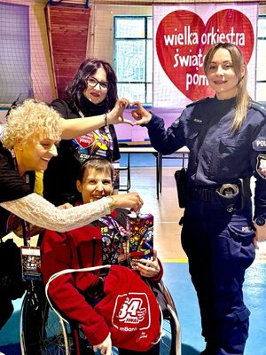 Umundurowana funkcjonariuszka Policji z uczestnikami finału zbiórki WOŚP