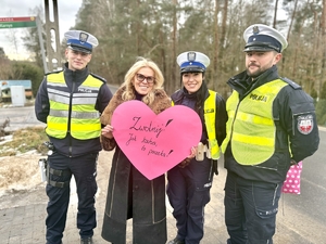 policjanci ruchu drogowego, stoi z nimi kobieta i trzyma serce z papieru