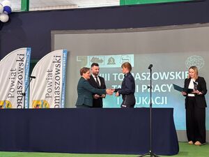 Umundurowana funkcjonariuszka Policji obierająca pamiątkowa statuetkę z rąk przedstawiciela organizatora.