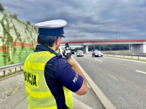 policjant stoi plecami do zdjęcia, w trakcie pomiaru prędkości