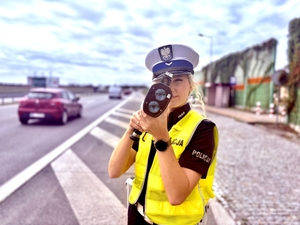 policjantka na pierwszym planie, w trakcie wykonywania pomiaru prękości