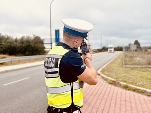 Umundurowany funkcjonariusz Policji mierzący prędkość.