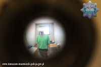 zatrzymany mężczyzna w policyjnej celi widoczny przez wizjer w drzwiach